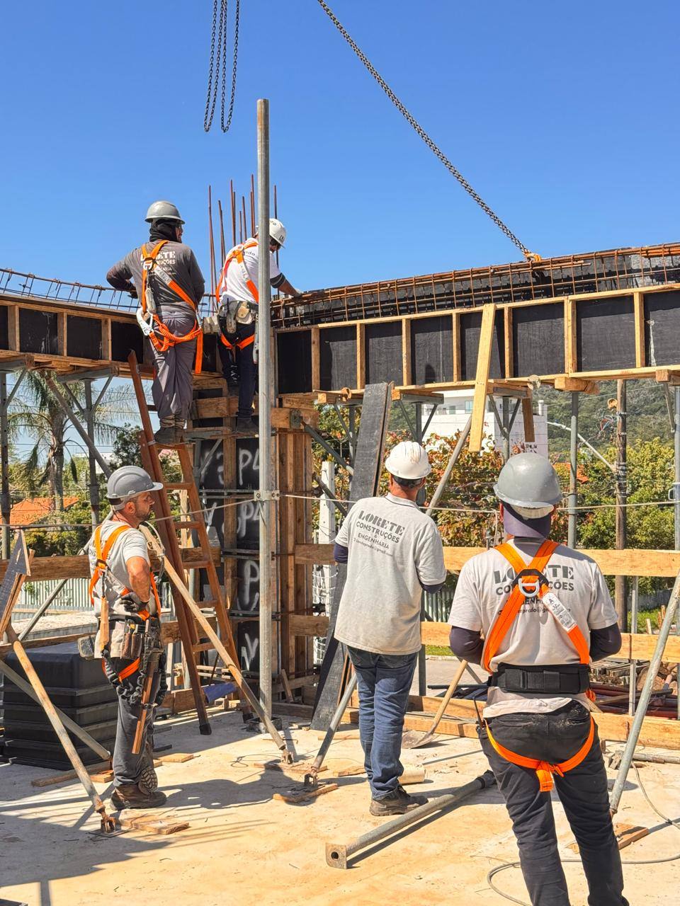 Equipe com cinto de segurança montando as formas da estrutura