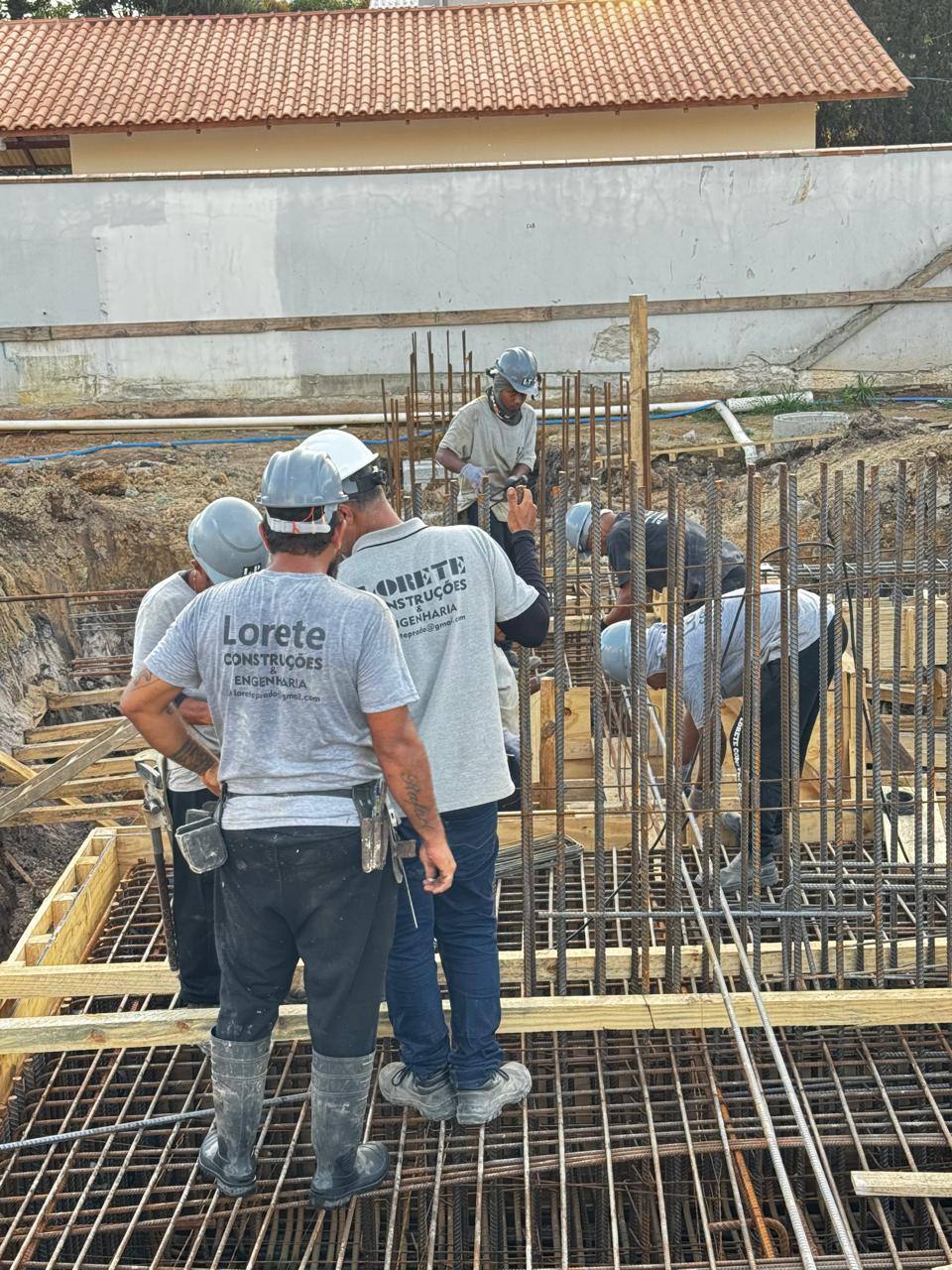 Equipe da Lorete Construções, de uniforme, montando a armação de uma fundação