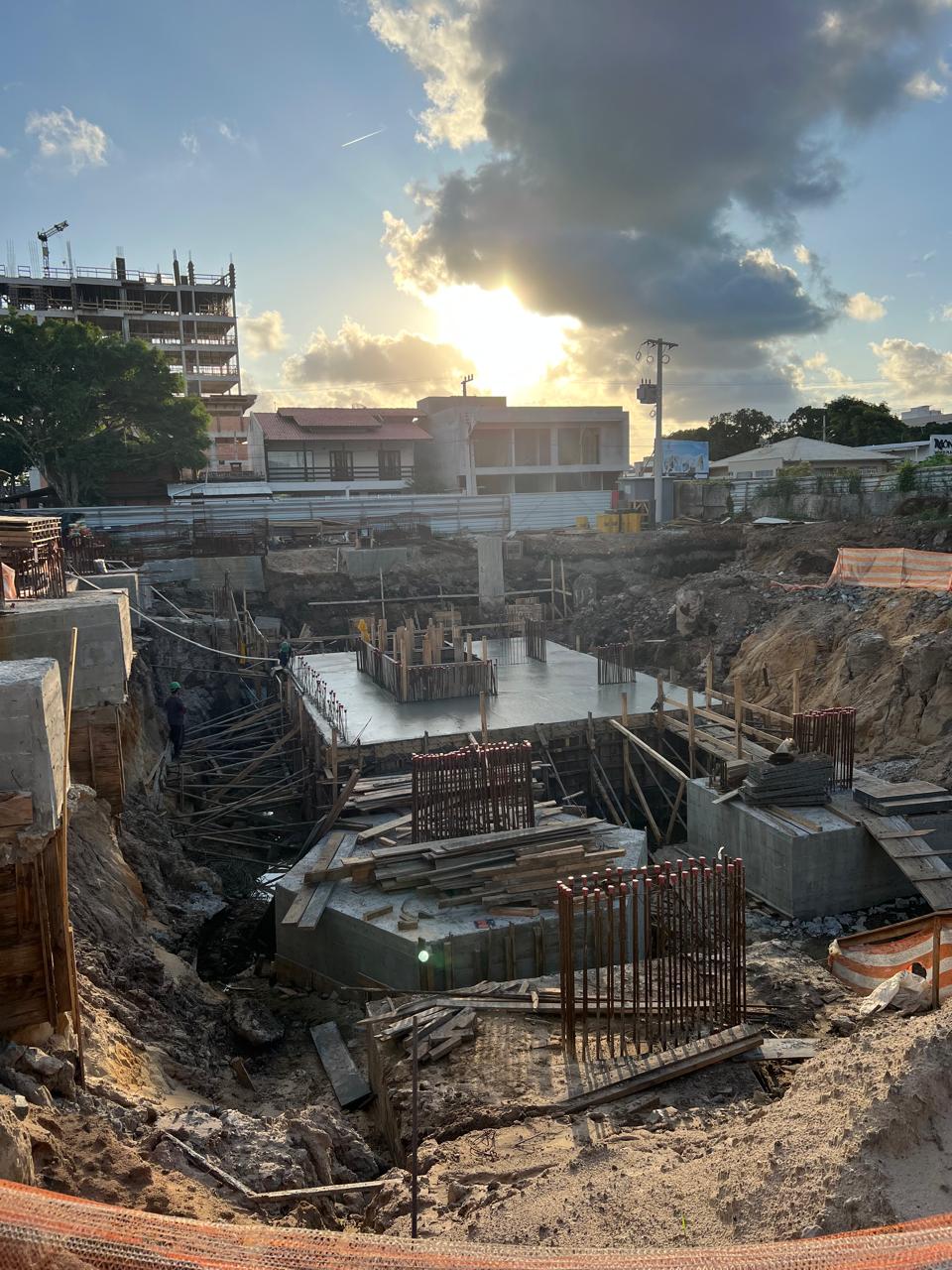 Canteiro de obra no fim da tarde, com a laje do subsolo concretada e os blocos de fundação