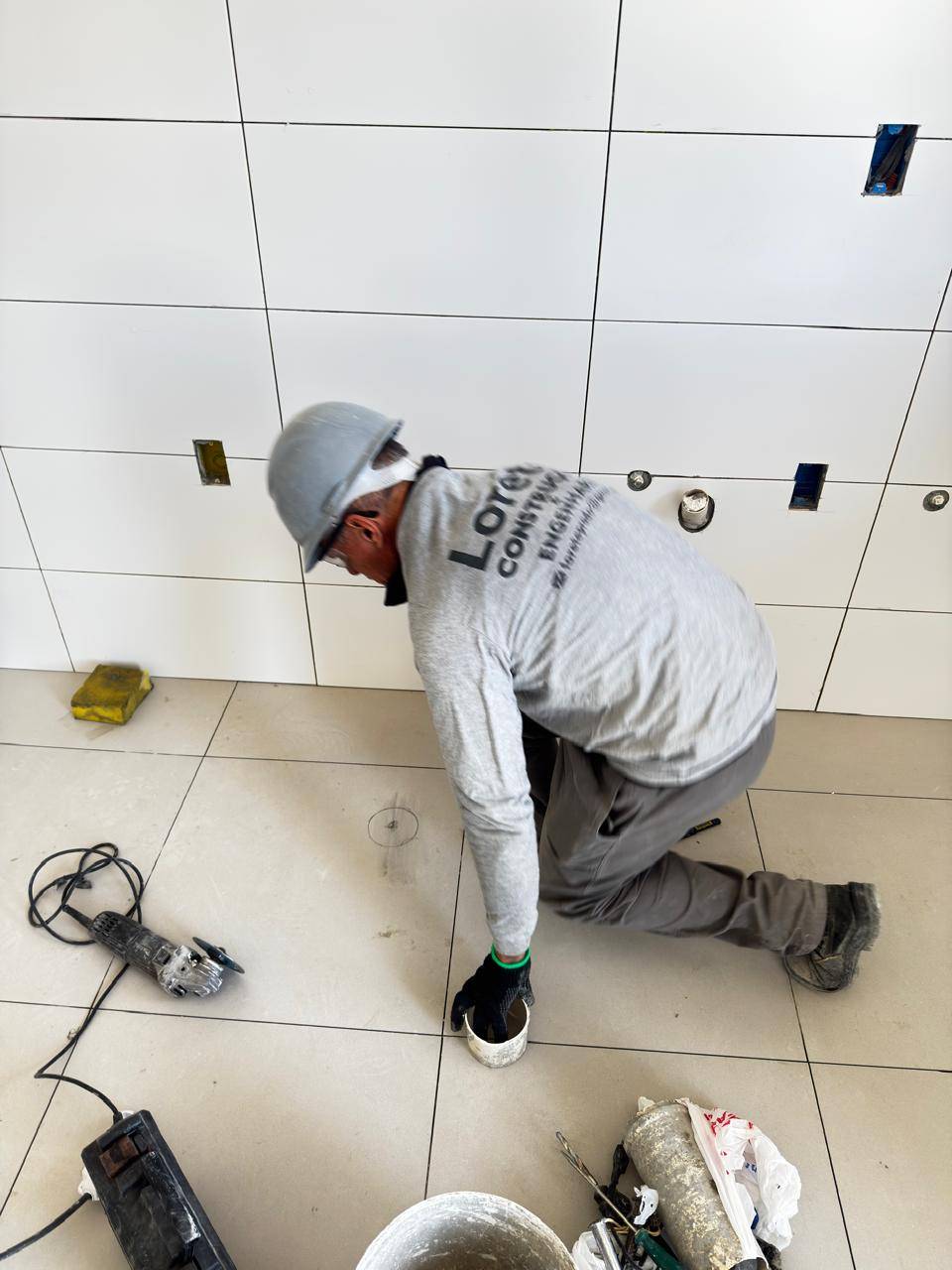 Profissional da Lorete Construções assentando porcelanato no piso
